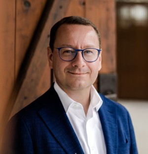 Portrait von Herrn Bürgermeister Sebastian Rötzer, im Hintergrund eine Holztür